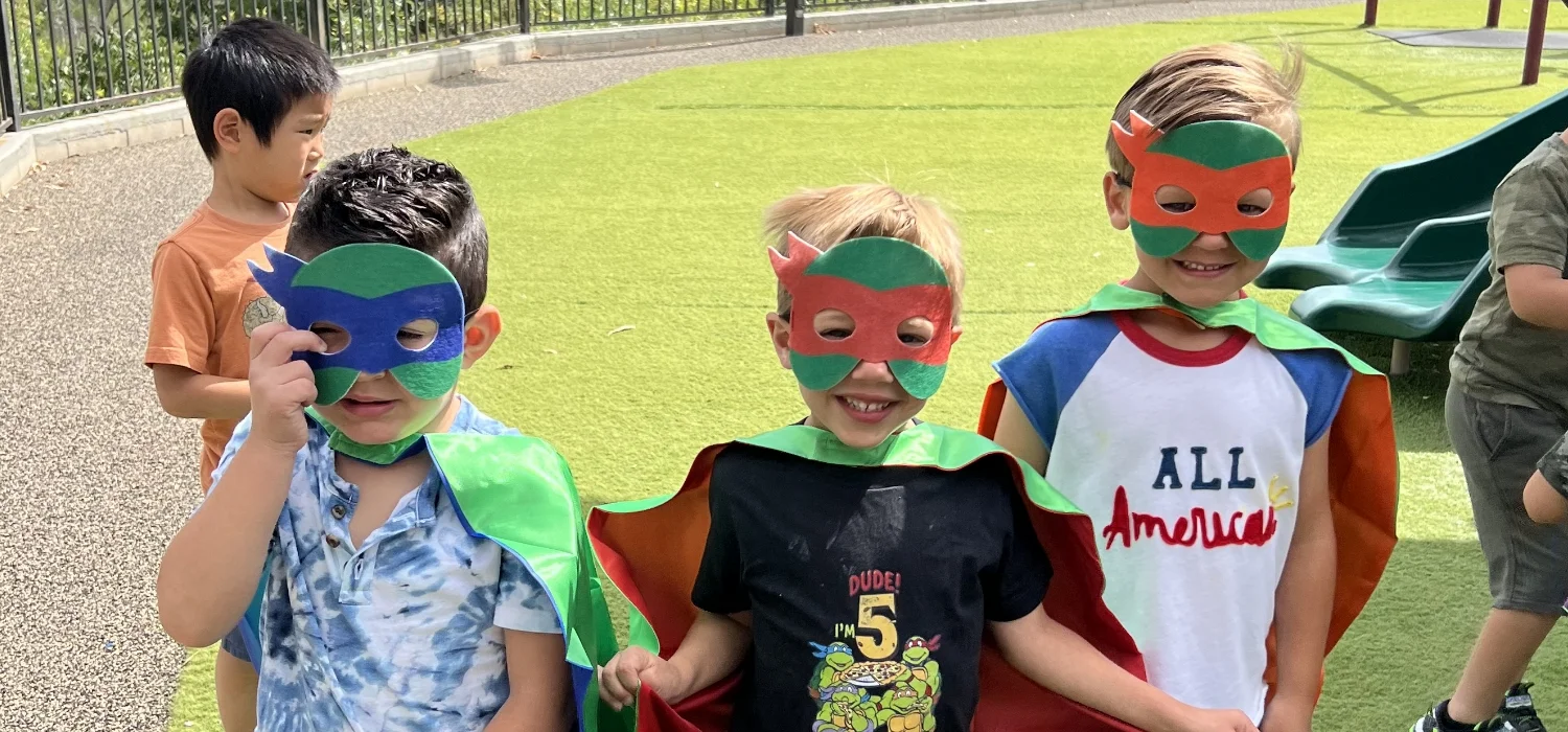 three students in superhero costumes