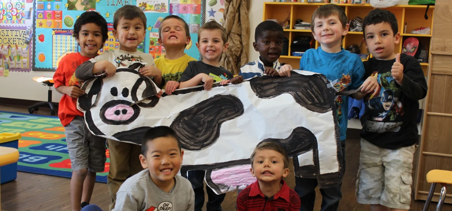 students holding up a paper cow